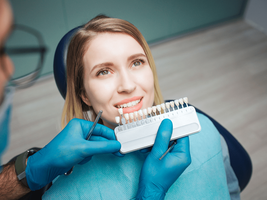 medicul stomatolog ii prezinta unei femei nuantele de alb pentru fatetele dentare