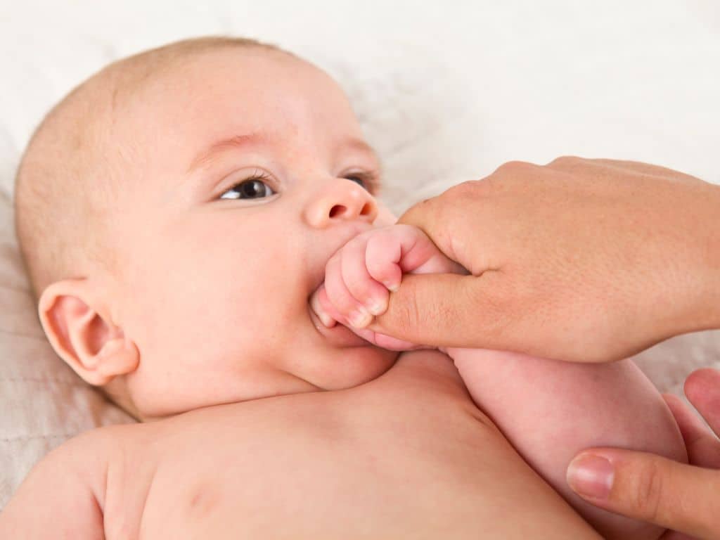 bebelus care isi suge degetul in timp ce este tinut de mana