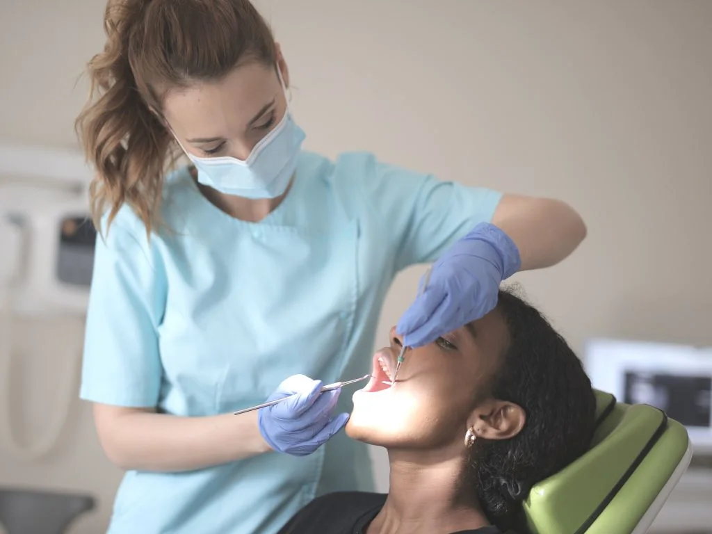 medic stomatolog care efectueaza o extractie dentara unei alte femei in cabinet